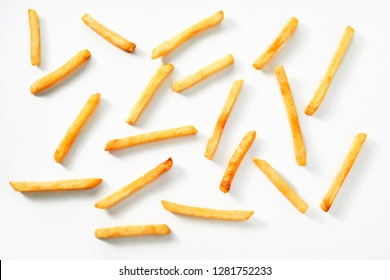 Scattered thin straight fried potato chips on a white background viewed from above