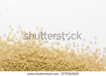 Scattered translucent plastic granules create clean abstract wave with copy space for recycling, manufacturing and material design.