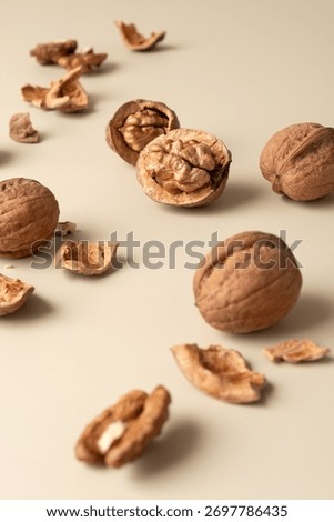 Scattered walnut shells and kernels on beige background. Minimal still life concept of natural food, simplicity, and healthy lifestyle.