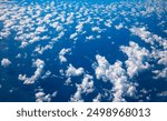 Scattered white clouds over the Indian Ocean. Aerial view from a commercial airplane at an altitude of approx. 26,000 ft after take-off in Mauritius on a sunny day. Light reflections on sea surface.