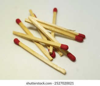 Scattered wooden matchsticks with red tips on a white background - Powered by Shutterstock