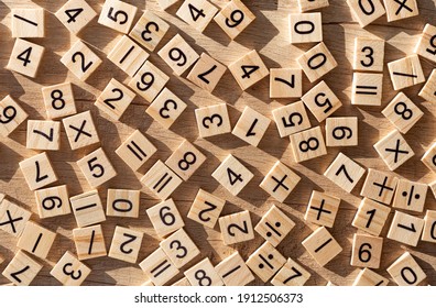 Scattered wooden plaques with numbers and signs. Flat lay. Teaching material in mathematics, Montessori method. School background. Problem solving concept. Laser cutting and printing on wood. - Shutterstock ID 1912506373