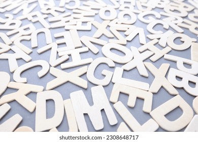 Scattered wooden white alphabets on gray background, English letters for learning English concept, glossary, words, and vocabulary