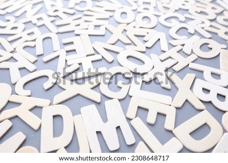 Scattered wooden white alphabets on gray background, English letters for learning English concept, glossary, words, and vocabulary