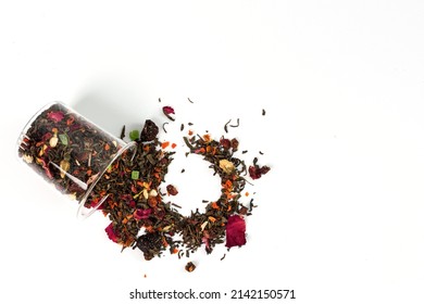 A Scattering Of Green, Leaf Tea In A Glass Transparent Jar On The Table. Fresh, Natural, Flavored Drink. Dry Leaves For Brewing Isolated On White Background. Place For Text