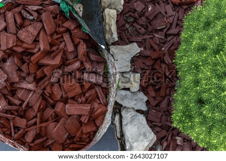 Scattering red tree bark around garden shrubs, acidifying the soil around garden plants, designing the garden space