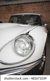Scena, Italy - June 03, 2016: frontal detail view of the spotlight of a white Jaguar E-type in a shelter