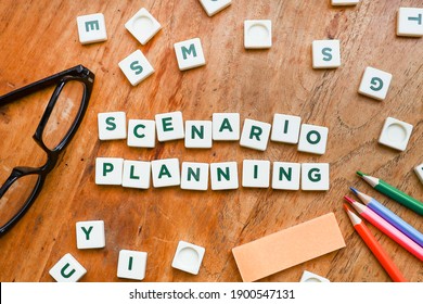 Scenario Planning On Block Letters On The Wooden Table With A Group On Color Pencils, And Eyeglasses