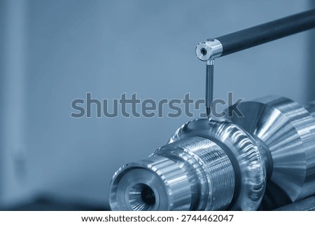 The scene captures a surface roughness measuring machine (profilometer) as its tactile stylus traverses the metal surface to quantify microscopic irregularities