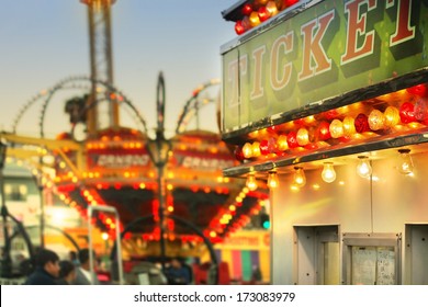 Scene at a classic carnival with a ticket booth in the foreground (focal point on the ticket sign) with overall subtle retro vintage tone and styling