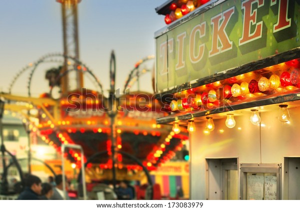 Scene at a classic carnival with a ticket\
booth in the foreground (focal point on the ticket sign) with\
overall subtle retro vintage tone and\
styling