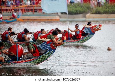 Szene eines Wettkampfbootes im traditionellen Dragon Boat Festival in Taipei, Taiwan, mit Athleten, die kräftig auf ihren Rudern ziehen und mit all ihrer Kraft in bunten Booten konkurrieren