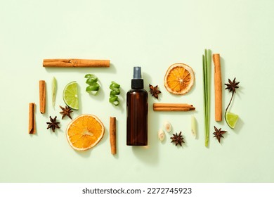 Scene mockup for product of natural flavoring extract with brown bottle without label, cinnamon sticks, illicium verum, lemon slice, dried orange slices and lemongrass on light background. Top view