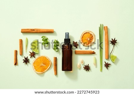 Scene mockup for product of natural flavoring extract with brown bottle without label, cinnamon sticks, illicium verum, lemon slice, dried orange slices and lemongrass on light background. Top view