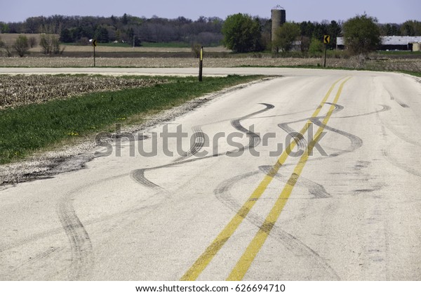 Scene of\
a near miss perhaps: Rural road with snaky tread marks near an\
abrupt turn, for themes of safe driving and avoidance,\
circumstance, suddenness and change of\
direction