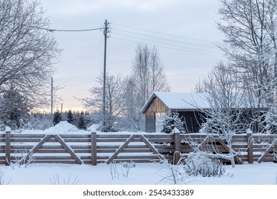 The scene showcases a charming rustic cabin enveloped in fresh snow, framed by frost-laden trees as twilight casts a soft glow over the winter landscape. - Powered by Shutterstock