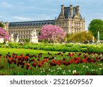 Scene from the Tuileries Gardens with flowers in the foreground, statues and architecture in the background during the spring in Paris, France. 