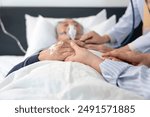 scene of a wife holding hands hopeless senior male patient who have oxygen and intravascular solution drip lying on bed,a doctor examining a dying patient,concept of palliative care,end of life care