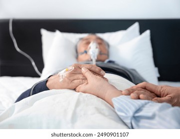 scene of a wife holding hands hopeless senior male patient who having oxygen and keep intravascular solution drip lying on bed,concept of palliative care,home care,hospital care,end of life care - Powered by Shutterstock