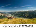Scenery alpine panorama of Switzerland in sunny day with view on Ovronnaz, mountains, green forest, meadows, blue sky and white clouds with a bench for rest in the foreground.