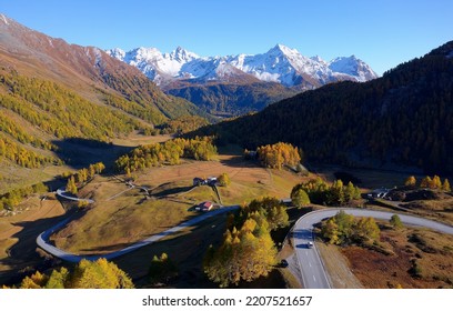 Scenery of beautiful Bernina Pass on a brisk fall day, with a highway winding thru golden larch forests and snowy alpine mountains towering under blue clear sky, in Grisons (Graubünden), Switzerland - Shutterstock ID 2207521657