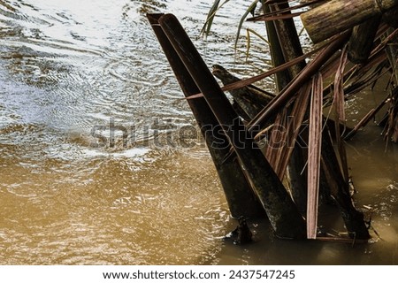 Scenery of broken beams timber wooden historical bridge constructed above tropical canal in dried water season.