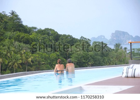 The scenery couple customers on rooftop swimming pool with tropical views