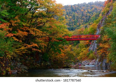 Scenery of the red Futami suspension bridge over Toyohira River with beautiful fall colors on the riverside cliffs in Jozankei (定山渓), a famous Onsen (hot spring) destination in Sapporo Hokkaido, Japan