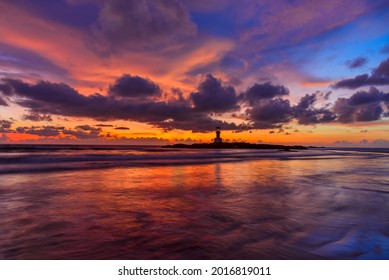 The scenery of the silhouette of Khao Lak Light Beacon in sunset time with the dramatic twilight sky at Nang Thong Beach, Phang Nga, Thailand. Silhouettes of the lighthouse in bright orange sunset sky