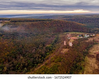 Scenic aerial sunset scenery with castle ruins (two towers) on the hill with forest inside the canyon and burning sky on background. Location place: Nyrkiv (Chervonohorod), Ukraine.