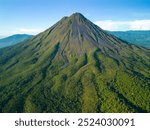 A scenic aerial view of Arenal Volcano in Costa Rica with lush green vegetation and clear blue sky