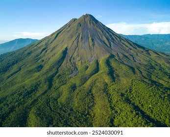 A scenic aerial view of Arenal Volcano in Costa Rica with lush green vegetation and clear blue sky