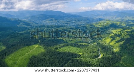 Scenic aerial view of the foggy Carpathian mountains, village and blue sky with sun and clouds in morning light, summer rural landscape, outdoor travel background