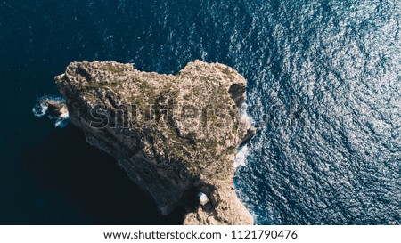 Scenic aerial view of small rocky island with precipice and green bushes in the blue mediterranean sea Gozo island, Malta