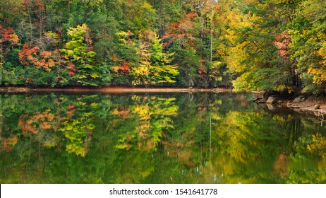 A scenic autumn view of colorful forest foliage reflecting on a lake.