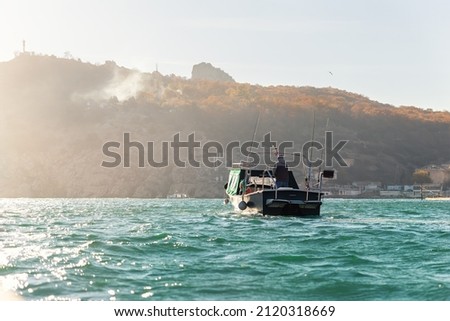 Scenic back view of fisherman angler enjoy fishing with rods on motor boat ship at clean green blue azure water harbor on early misty morning sunrise. Fishing speedboat with angling man at foggy bay