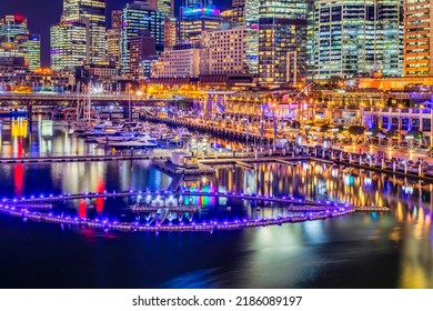 Scenic Brightly Illuminated Darling Harbour Waterfront In Sydney City CBD At Sunset With Water Fountain Floaging On Coockle Bay.