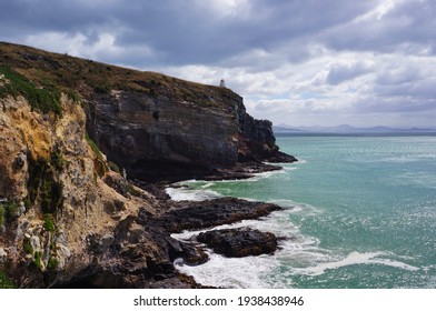 Scenic Cliff landscape with dramatic clouds and small lighthouse in the back