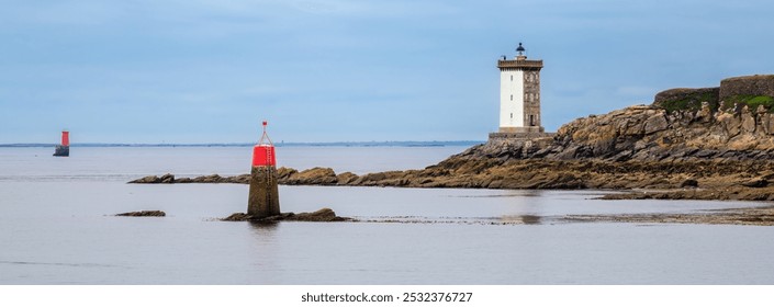 A scenic coastal panorama featuring a lighthouse Phare de Kermorvan on rocky terrain and two red navigation buoys in calm waters under a cloudy sky. - Powered by Shutterstock