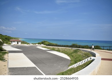 Scenic Coastal Path with Cyclist and Clear Blue Sea – Serene Beachfront View - Powered by Shutterstock