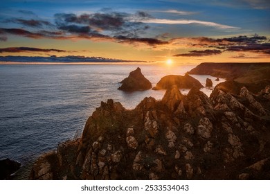 Scenic coastal sunset view with rugged cliffs and calm ocean waters, featuring vibrant sky colors and dramatic rock formations. - Powered by Shutterstock