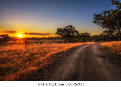 Scenic countryside landscape with rural dirt road at sunset in Australia
