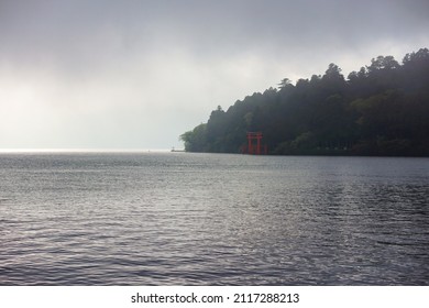 Scenic Dark View Of Lake Ashi In Hakone, Japan With Forest And Red Torii Gate And Cloudy Sky Background. No People.