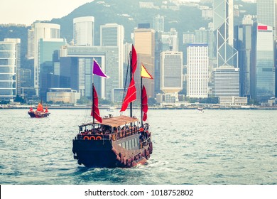 Scenic Daytime Skyline Of Hong Kong Island With Skyscrapers And Traditional Boats Sailing.