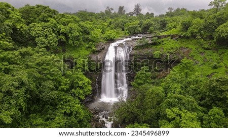 A scenic drone view of Vihigaon Ashoka waterfalls flowing through rocks surrounded by lush greenery