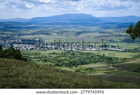 Scenic elevated view of Eger’s outskirts and the distant Mátra Mountains from the grassy western slopes of Nagy-Eged Hill, Hungary.