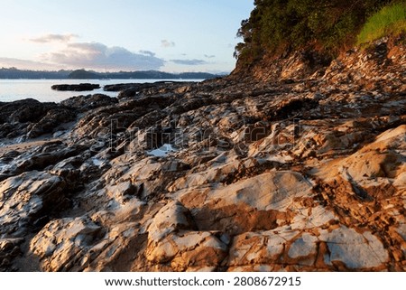 Scenic flat jagged and patterned rocky headland at south end of Paihia waterfront in Northland New Zealand.
