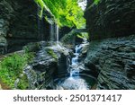 A scenic forest waterfall with multiple cascades, a stone bridge, and lush greenery creates a serene, Watkins Glen State Park, Pennsylvania