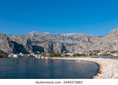Scenic hiking trail Omiski lukobran in coastal town Omis, Split-Dalmatia, South Croatia, Europe. Majestic rugged coastline of Omis Riviera surrounded by steep Dinara mountains. Balkans in summer