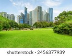 Scenic Kuala Lumpur skyline. Amazing view of a green city park in Kuala Lumpur, Malaysia. High-rise buildings are visible on blue sky background. Kuala Lumpur is a popular tourist destination of Asia.